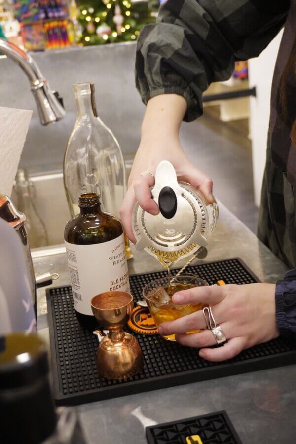 All-Ages Adventure: The Ultimate Trip to Louisville, KY - 13 A person strains a drink into a glass at a bar setup, with a bottle, jigger, and bar tools visible on the counter—highlighting one of the classic things to do in Louisville for cocktail enthusiasts.