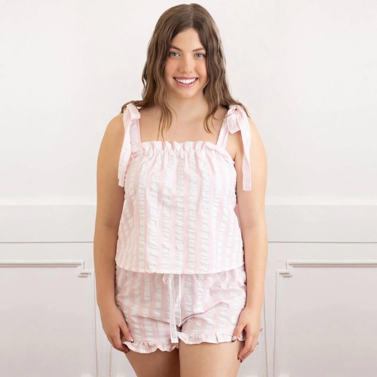15 Memphis FINDS for May: Mother's Day & Spring Celebrations - 2 A woman stands indoors wearing a pink and white striped sleeveless pajama set with tie straps, smiling at the camera after a successful Memphis shopping trip.