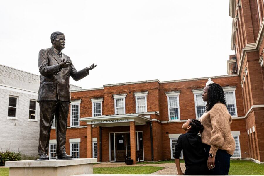 Why Hattiesburg Might Be Mississippi’s Biggest Surprise - 6 A woman and child stand in front of a bronze statue of a man outside the Hattiesburg District Attorney's Office in Mississippi.
