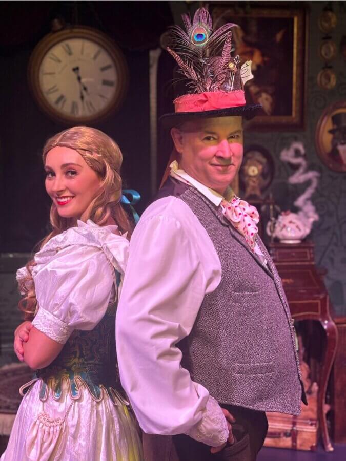 Why Hattiesburg Might Be Mississippi’s Biggest Surprise - 4 Two adults in costume stand back-to-back in Hattiesburg; the woman wears a blonde wig and white dress, while the man sports a feathered top hat and vest, set against vintage Mississippi decor with a clock as the biggest surprise.