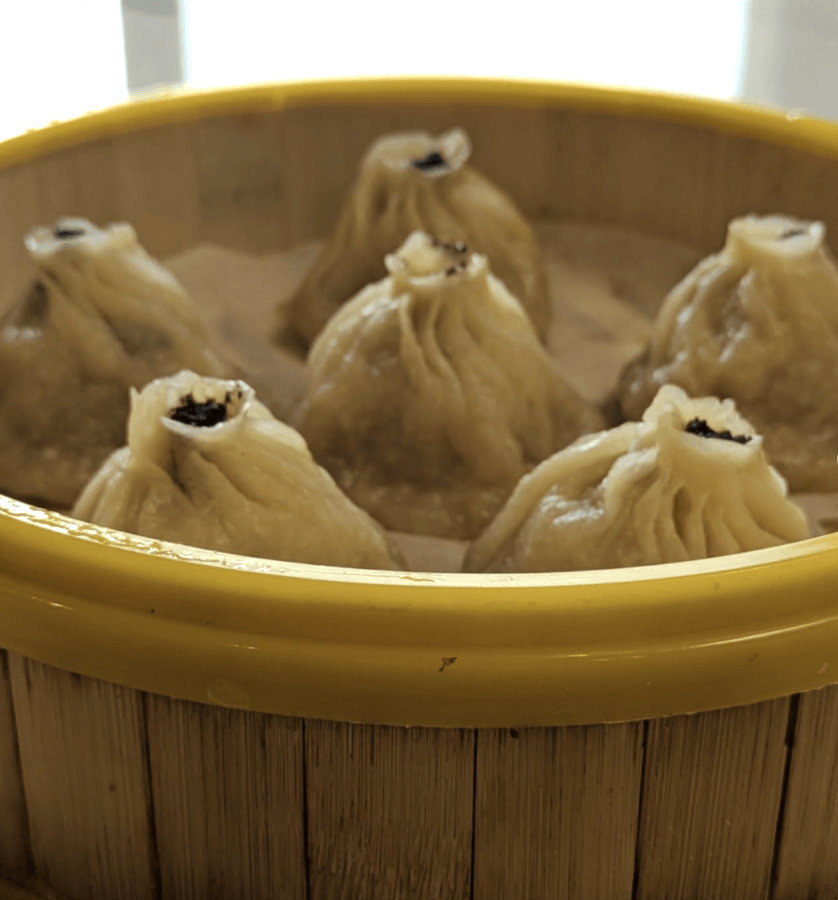 5 New Memphis Restaurants to Try This Month (+ What's Coming Soon!) - 4 Six steamed soup dumplings arranged in a bamboo basket with a yellow rim.