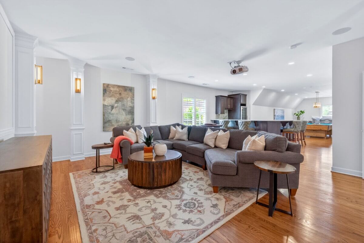 Just Listed! A Thoughtfully Designed Franklin Home That Delivers on Every Level - 13 Spacious living room at 2708 Eglington Terrace with a gray sectional sofa, round wooden coffee table, patterned rug, wall art, hardwood floors, and open view into dining and kitchen areas.