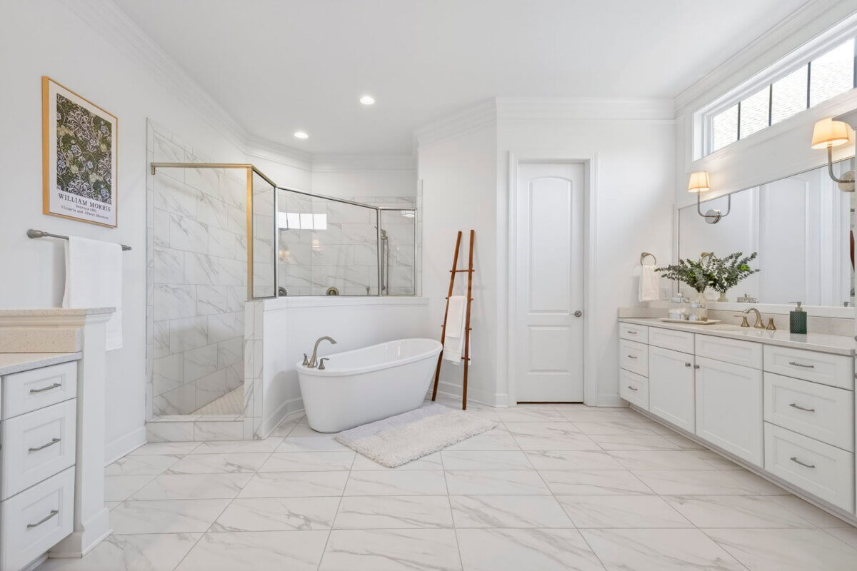 Just Listed! A Thoughtfully Designed Franklin Home That Delivers on Every Level - 11 Spacious modern bathroom with white cabinets, freestanding bathtub, glass shower, double sinks, and large mirrors on white tile flooring.