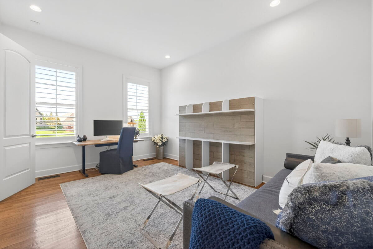 Just Listed! A Thoughtfully Designed Franklin Home That Delivers on Every Level - 12 Bright home office features a desk, computer, and chair by two windows; a sofa, rug, shelving, and two stools complete the minimal, modern decor.