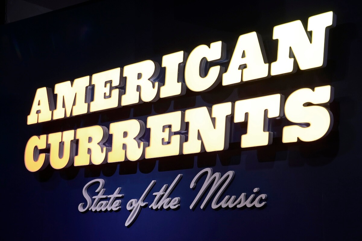 Illuminated sign reads "AMERICAN CURRENTS State of the Music" with bold yellow and white lettering on a dark background, marking a striking entrance to the American Currents exhibit at the Country Music Hall of Fame.