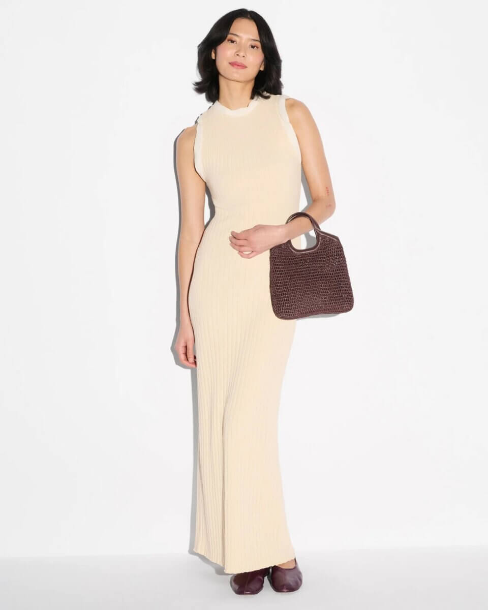20 Spring FINDS for Mother’s Day & Beyond: Style, Beauty & Home Must-Haves - 3 A person wearing a sleeveless, beige, ribbed maxi dress holds a brown woven handbag and stands against a plain white background, ready for a stylish day out in Nashville—perfect inspiration for your FINDS Draft this May 2026.