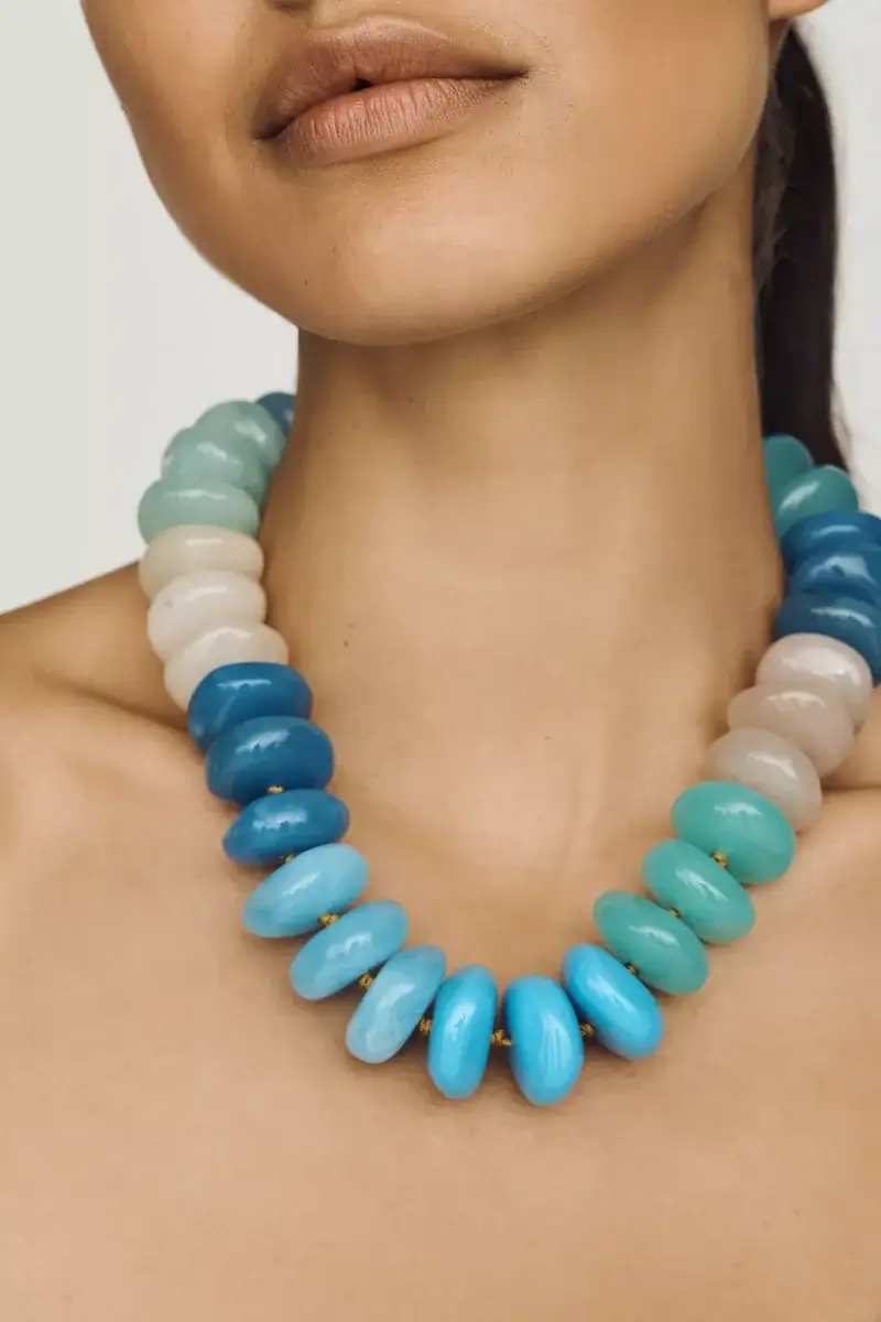4 Easy, Breezy Fashion Trends for Summer 2026 - 12 Woman wearing a chunky beaded necklace with large, round beads in shades of blue, turquoise, and white.