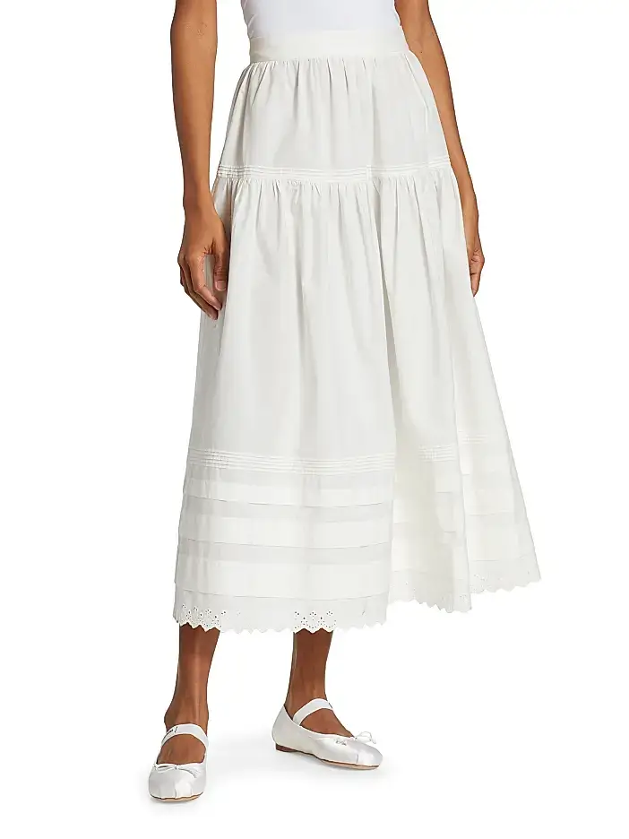 4 Easy, Breezy Fashion Trends for Summer 2026 - 10 A woman wearing a white tiered midi skirt with eyelet trim at the hem, paired with white ballet flats and a white top—a fresh look inspired by 2026 summer trends.