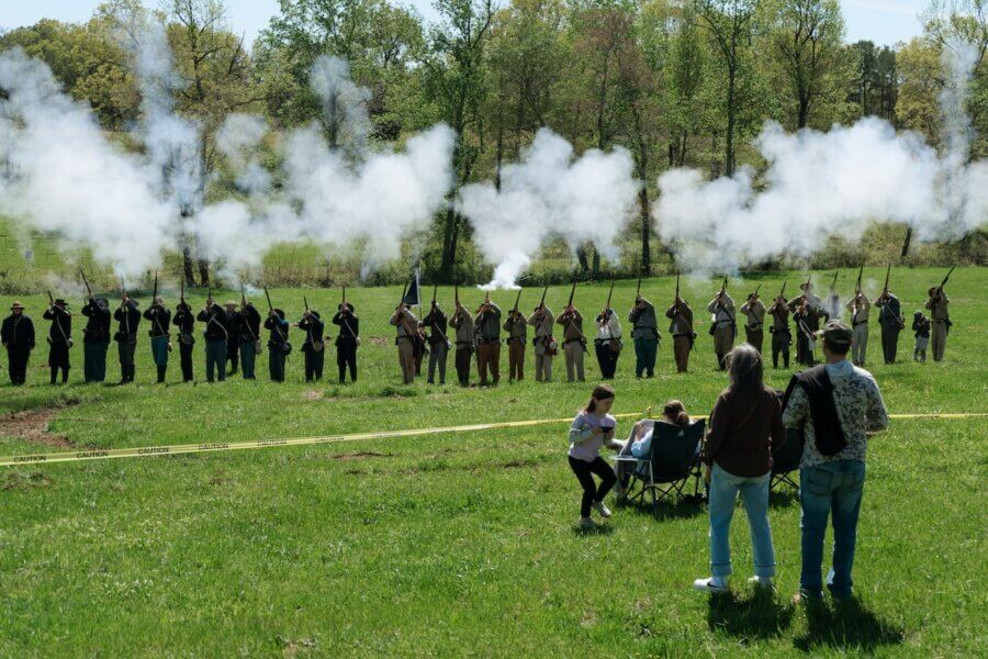 Living History: 7 Tennessee Towns Where the Past Comes Alive - 12 A Civil War reenactment is underway in a grassy field of one of the region’s historic towns, with two lines of participants in period uniforms firing rifles as spectators watch from behind yellow tape.
