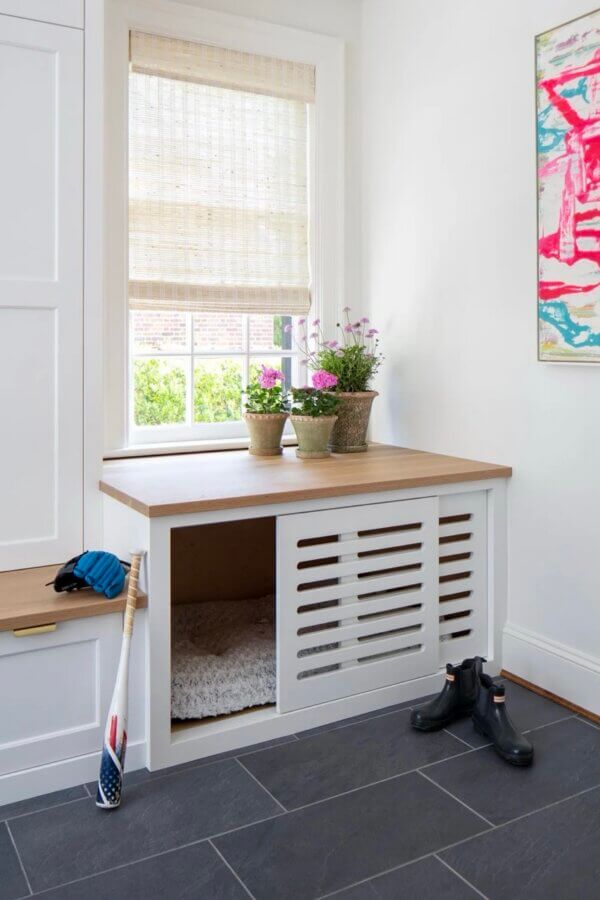 It Started with Wallpaper: Look Inside This Reimagined Richmond Colonial - 10 A built-in nook with a wooden top, potted plants, and a cushion for a pet is set under a window; nearby are boots, a baseball glove, and a bat.