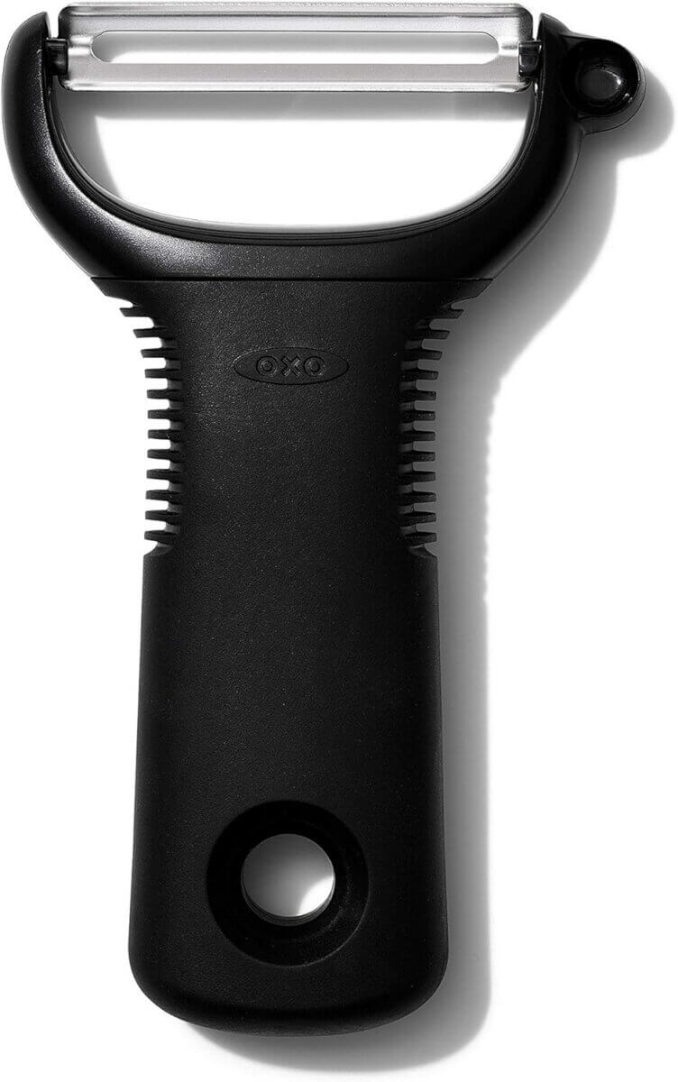 Chefs' Kitchen Tools Worth the Splurge (and Some to Save On) - 9 A black Y-shaped vegetable peeler from essential chef tools, featuring a stainless steel blade and a hole at the handle's end, placed on a white background.