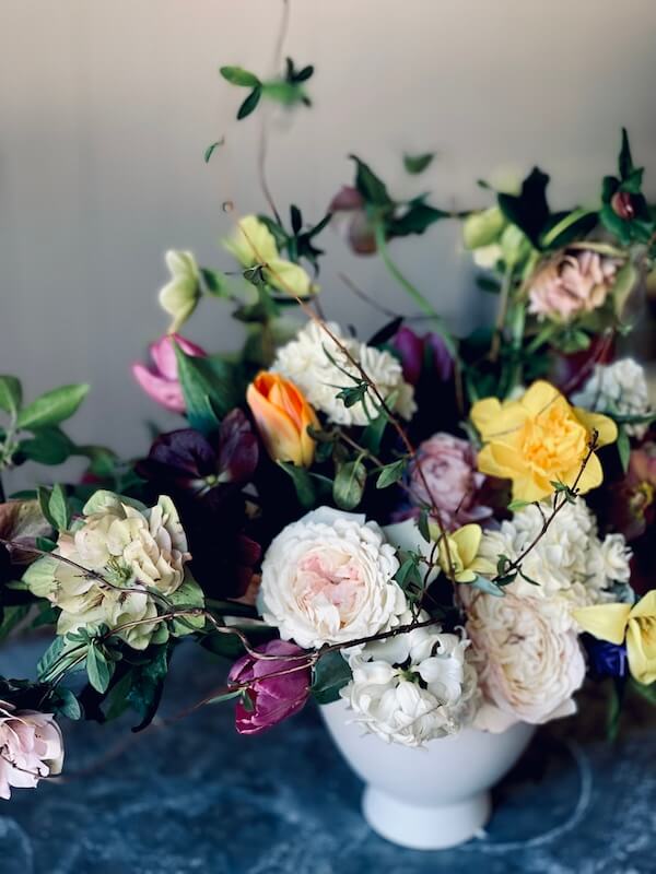 Meet the Nashville Grower Behind Bloom & Bounty - 6 A white ceramic vase from Meredith Bishop, filled with a variety of colorful flowers and lush greenery, including roses, tulips, and foliage.