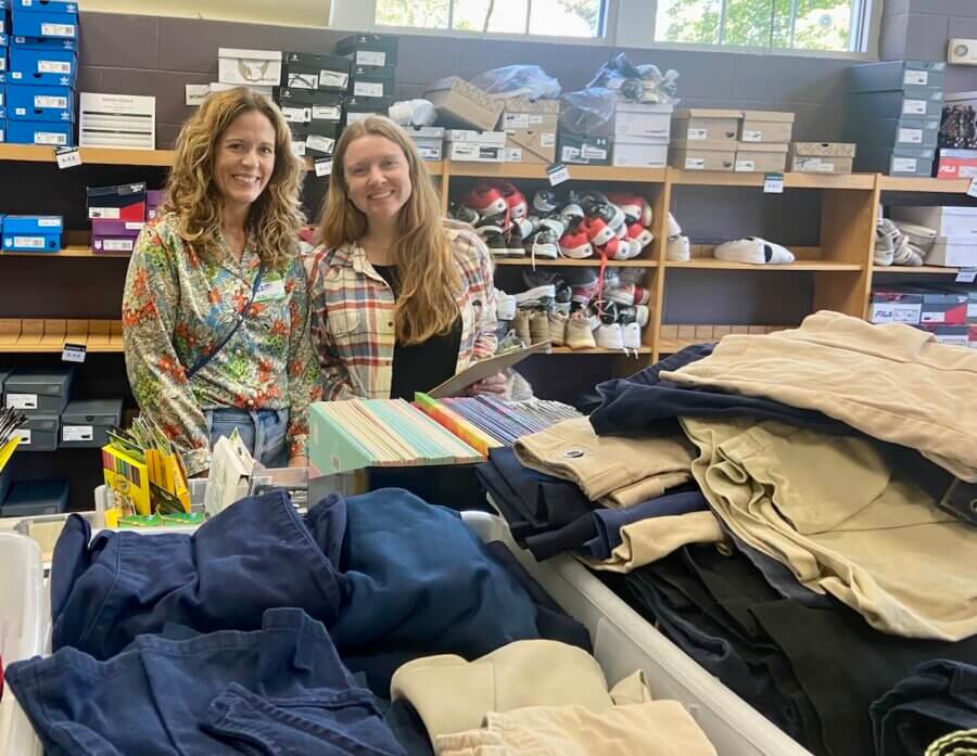 It Started with a StyleBlueprint Story — Now This Nashville Nonprofit Is Turning 10! - 4 Two women standing and smiling in a room with shelves of shoes and boxes behind them, folded pants and school supplies on a table in the foreground, highlighting Nashville community connections.