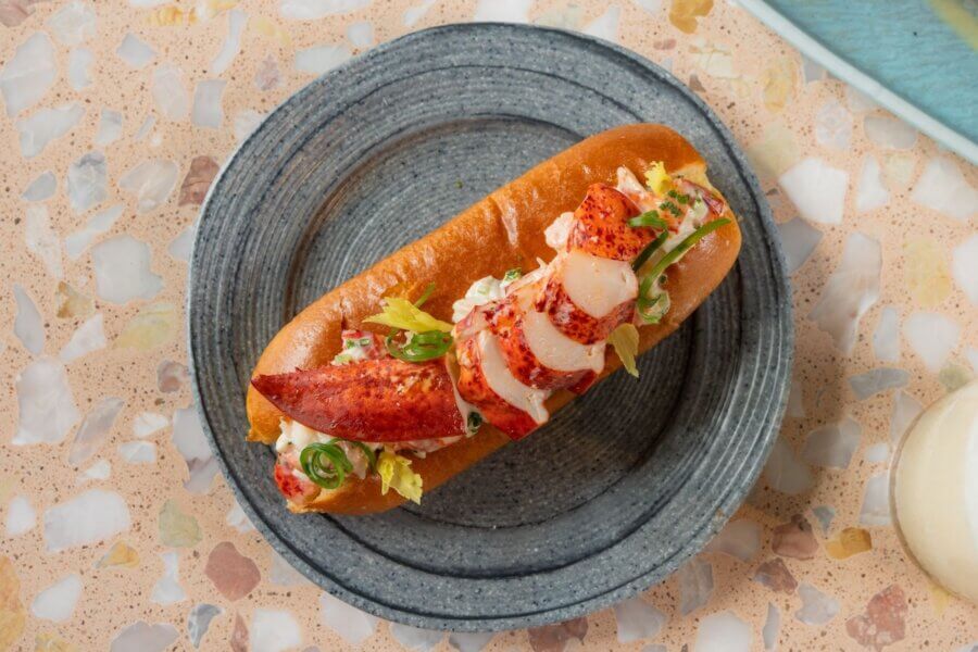 Lobster roll served on a round gray plate, filled with lobster meat, lettuce, and garnished with green onions—a must-try at new restaurants opening in Nashville restaurants by April 2026.