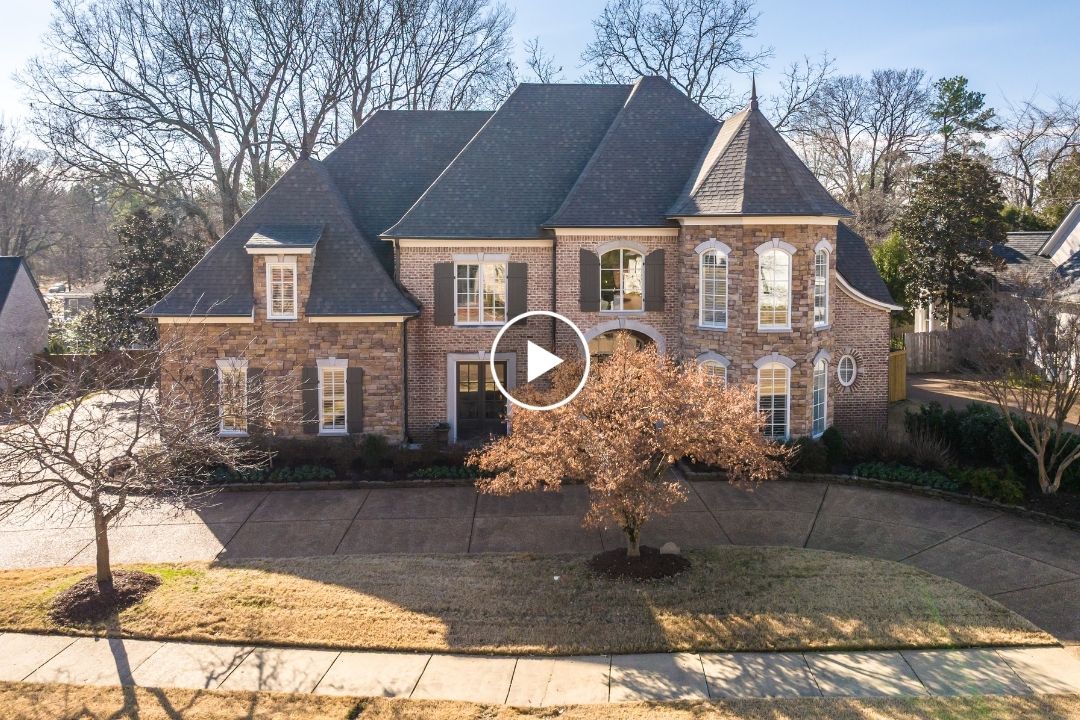 Large two-story brick house with arched windows, steep roof, and manicured landscaping on a circular driveway at 7571 Tagg Dr, Germantown TN, photographed on a sunny day.