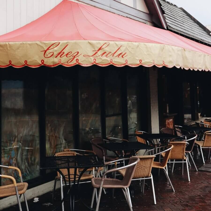 Your Guide to Mountain Brook's Villages - 16 Outdoor seating area with empty chairs and tables under a red and yellow striped awning that reads "Chez Lulu," located in the heart of Mountain Brook Village—your perfect guide to an inviting dining spot.