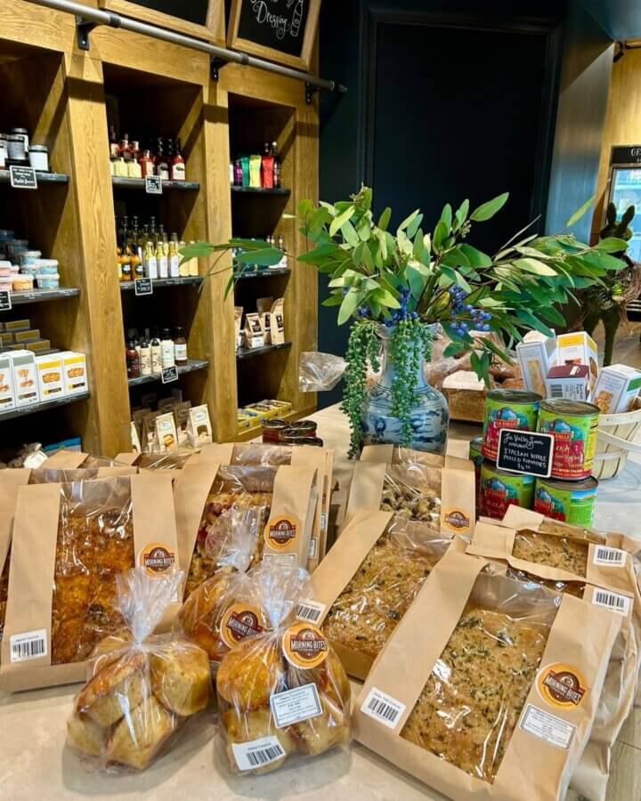 Your Guide to Mountain Brook's Villages - 8 A display of packaged baked goods on a counter in Mountain Brook, with shelves of assorted food products and a vase with greenery in the background. Perfect for any Mountain Brook guide.