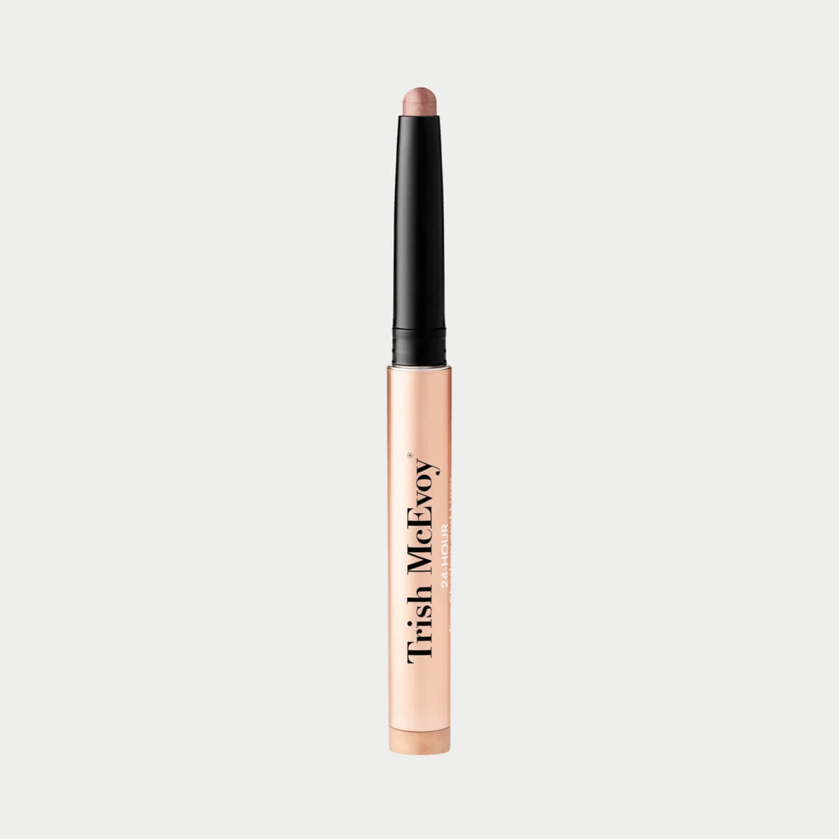 A rose gold-colored eyeshadow stick with a twist-up mechanism, labeled "Trish McEvoy," shown against a plain light background.