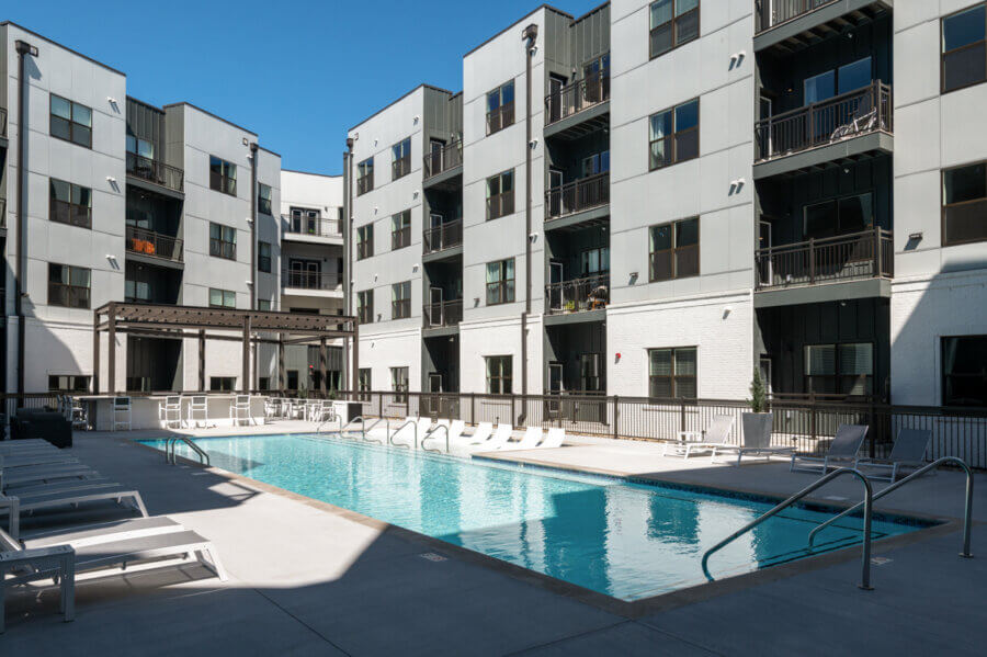 Rectangular outdoor swimming pool surrounded by lounge chairs and railings in the courtyard of a modern Nashville apartment complex—perfect real estate at 1677 54th Ave N.