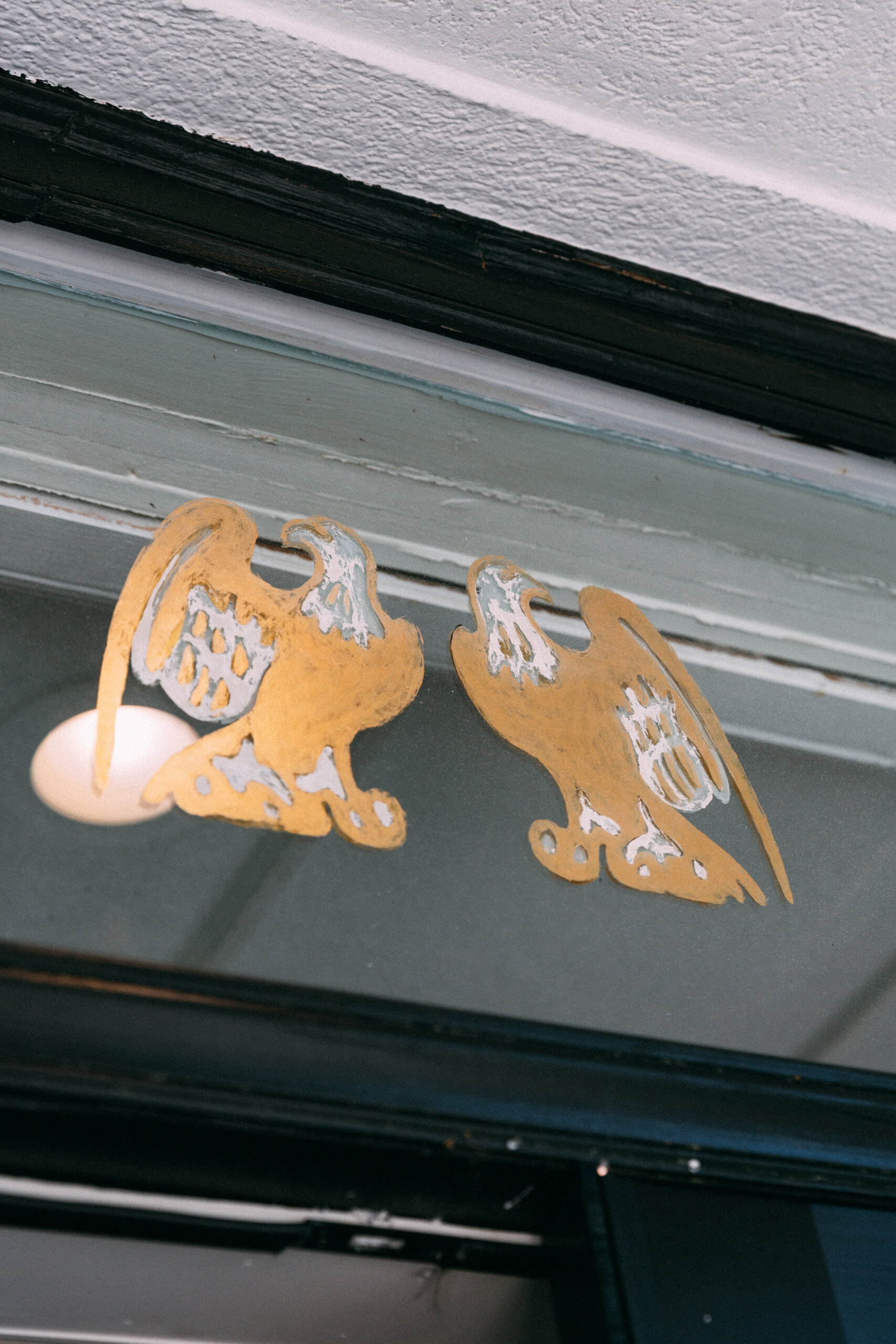 A Masters-Inspired Design Project You Need to See - 12 Two gold eagle decals with worn details, perfect for a Design Project, are displayed on a glass window or door beneath a white ceiling.