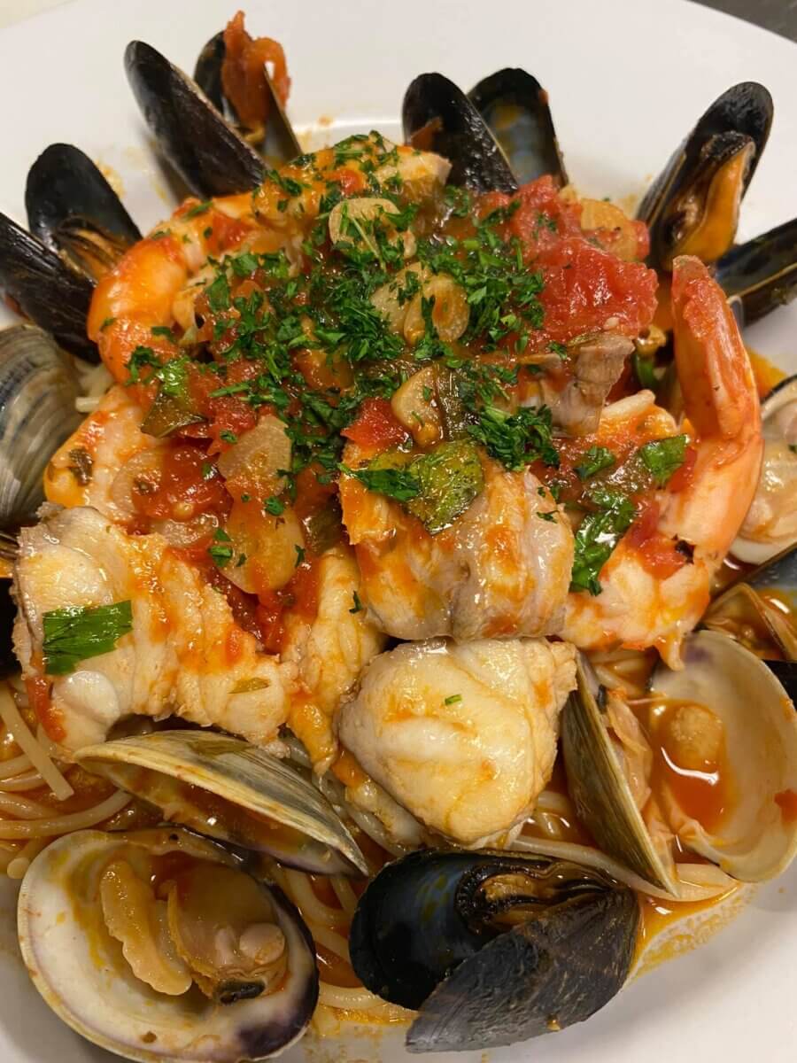 The South's Oldest Restaurants, Still Operating Today - 5 A plate of seafood pasta topped with tomato sauce, shrimp, white fish, mussels, clams, and chopped herbs—a classic dish.