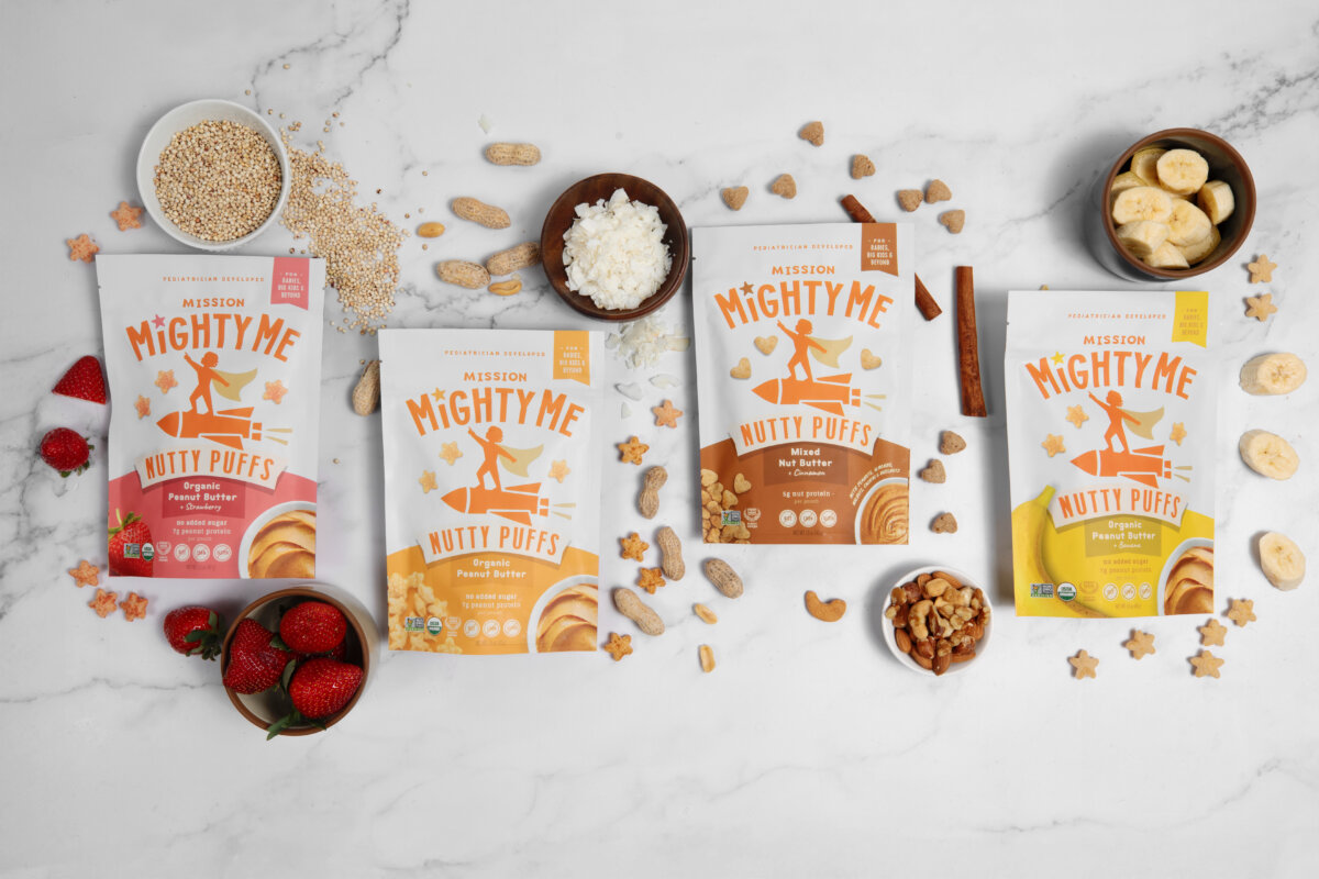 This Mom is on a Mission to Change the Future of Food Allergies - 5 Four bags of Mission MightyMe Nutty Puffs snacks are arranged on a marble surface with bowls of ingredients like banana chips, peanuts, strawberries, cottage cheese, and grains.