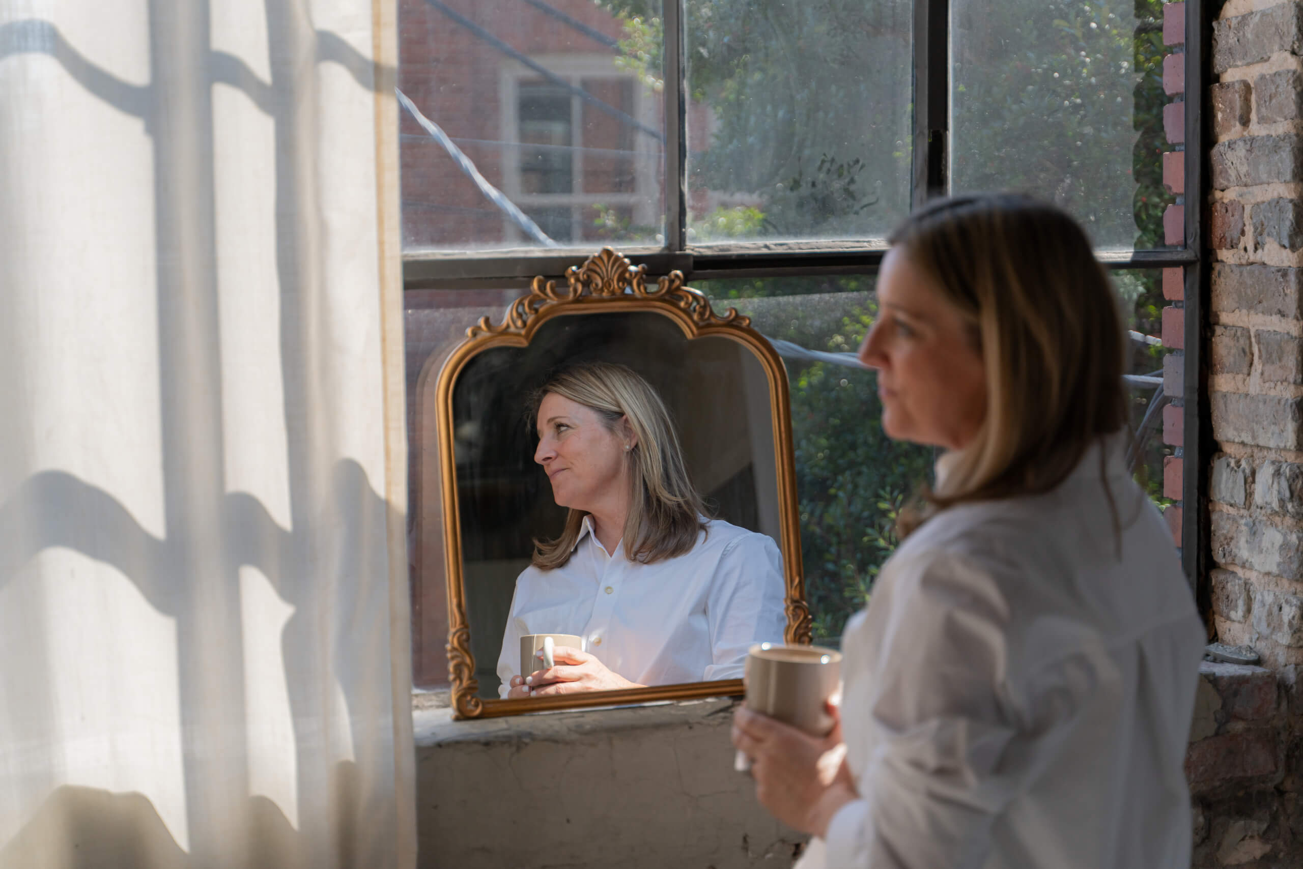 Is It Time for Hormone Therapy? What You Need to Know - 7 A woman Is holding a mug of coffee while standing in front of a mirror.