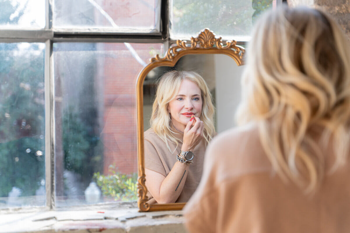 Is It Time for Hormone Therapy? What You Need to Know - 4 A woman applying lipstick in a mirror.