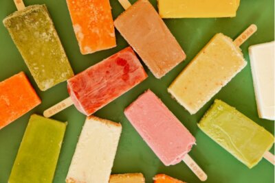 Assorted colorful popsicles arranged on a green surface, each with a visible wooden stick—perfect for enjoying after exploring new restaurants in Birmingham.