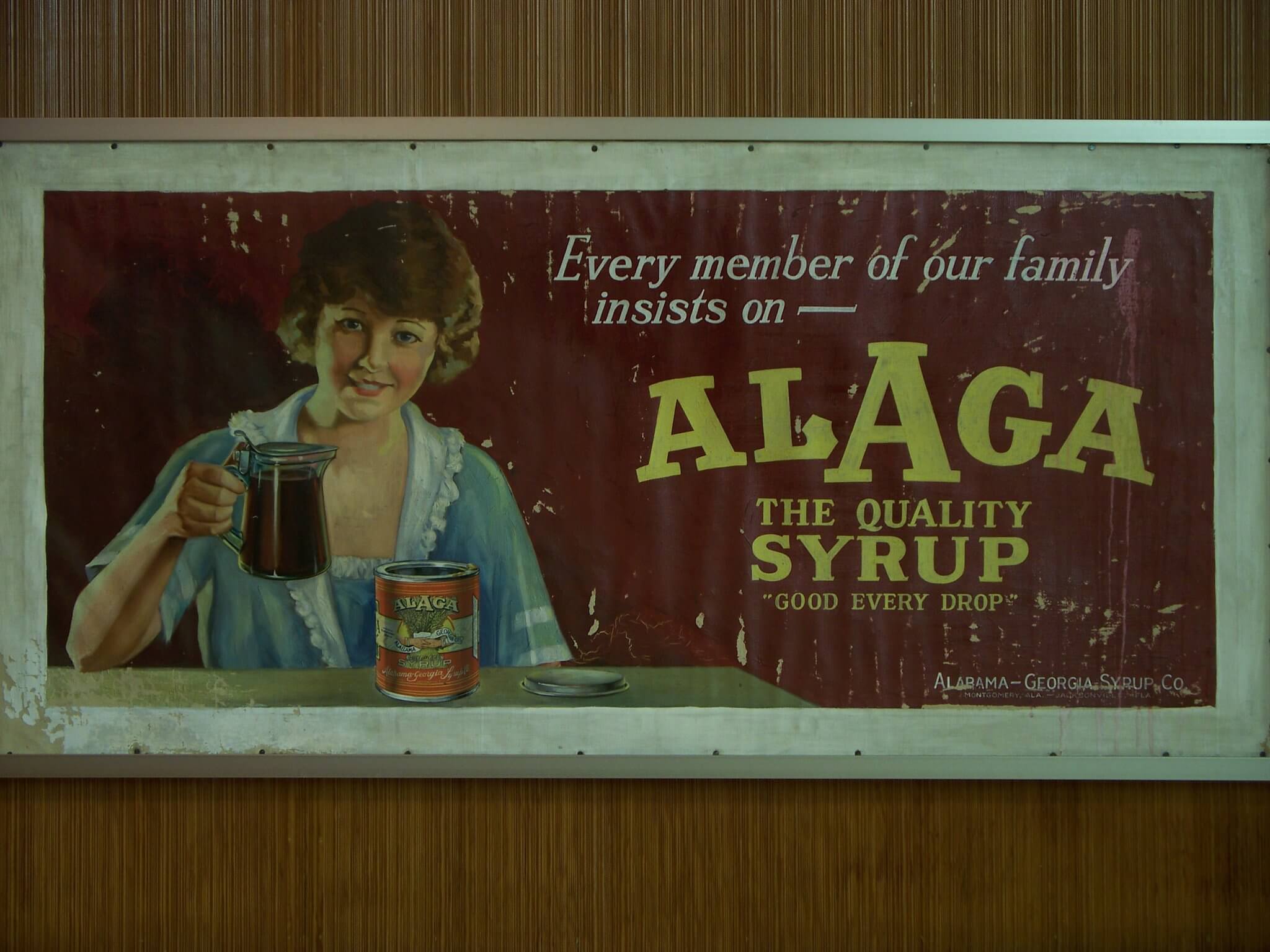 ALAGA Syrup: Alabama's IYKYK Staple - 4 A vintage advertisement features a woman holding a pitcher of syrup next to a can, promoting ALAGA Syrup—an Alabama staple—with the slogan, "Every member of our family insists on Alaga.