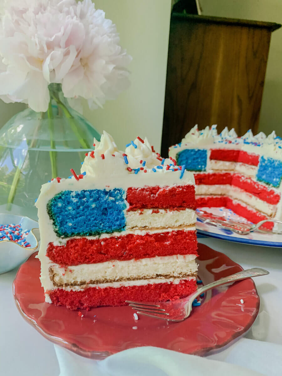 Meet Sally McKay, the Founder of Sally's Confections - 4 A slice of layered cake decorated to resemble the American flag, with red, white, and blue layers, white frosting, and red, white, and blue sprinkles.