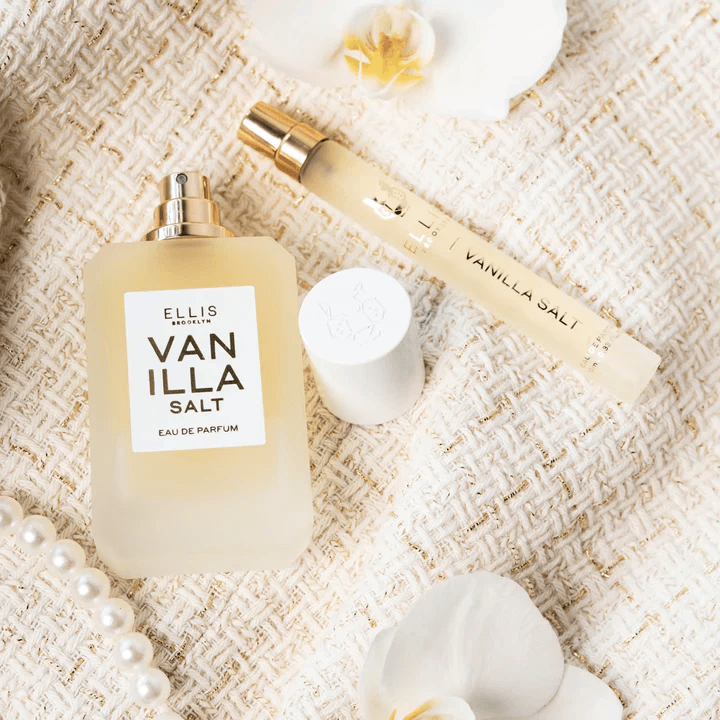 20 Nashville FINDS for June: Father's Day Gifts, Chic Accessories & More - 11 A bottle and a travel spray of Ellis Brooklyn Vanilla Salt perfume are placed on a textured fabric with pearls, white flowers, and a gold lid—perfect for your May must-haves or as one of our favorite Nashville FINDS.