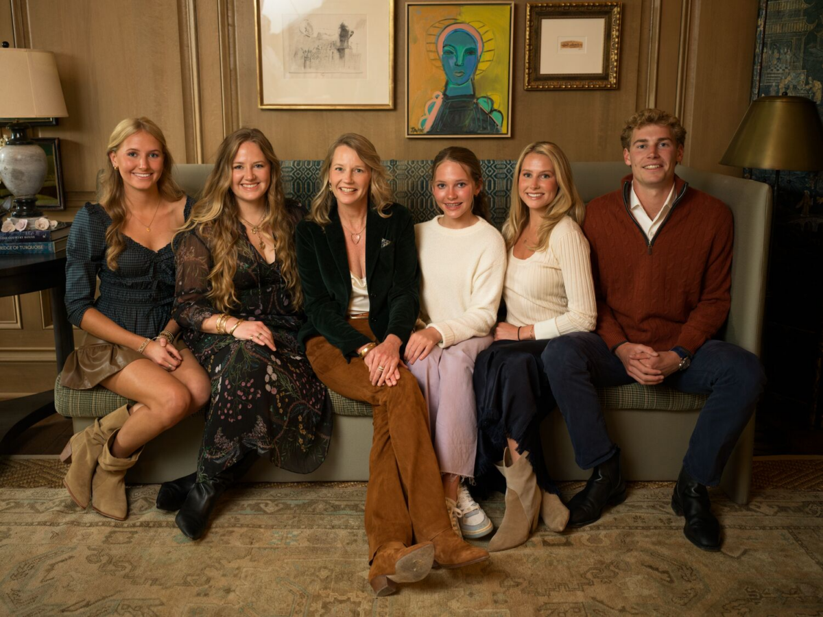 Meet the Woman Behind Tennessee's Beloved Blackberry Farm - 8 Six people sit together on a couch in a warmly lit room at Blackberry Farm with wooden walls and framed art, posing and smiling for the camera.