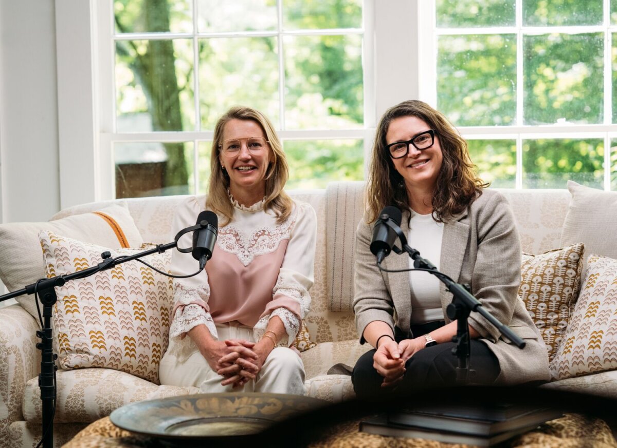 Meet the Woman Behind Tennessee's Beloved Blackberry Farm - 6 Two women sit on a couch in front of microphones, smiling at the camera, with large windows and greenery at Blackberry Farm visible in the background.