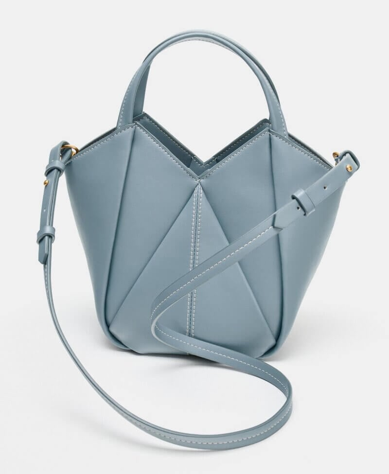 Light blue geometric-shaped handbag with a top handle, adjustable shoulder strap, and visible white stitching—a standout piece for those who love colorful bags, displayed on a plain background.