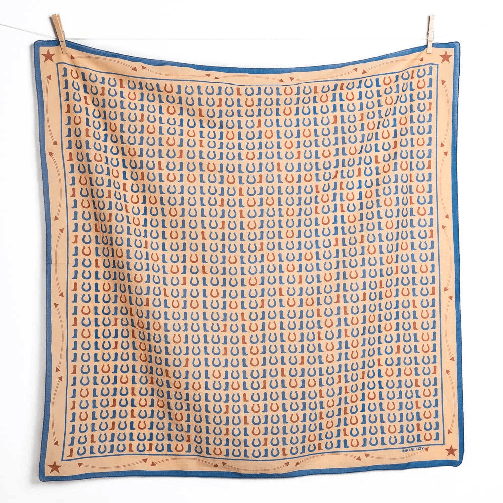 20 Nashville FINDS for June: Father's Day Gifts, Chic Accessories & More - 8 A square scarf from May FINDS, featuring a blue and orange horseshoe pattern with a border of red stars, displayed hanging on a line with clothespins—a charming Nashville-inspired accessory.