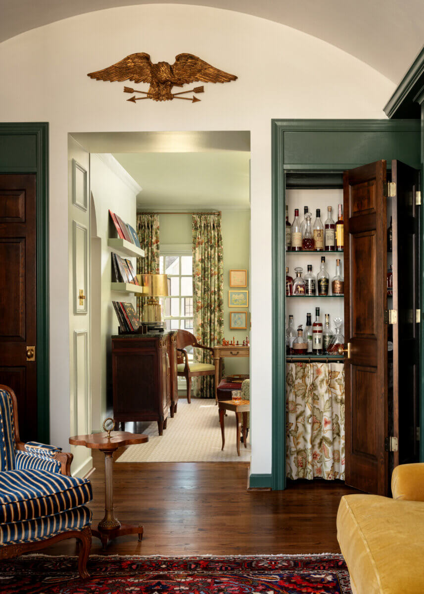 A sitting room features a hidden bar, and a living room in the background.