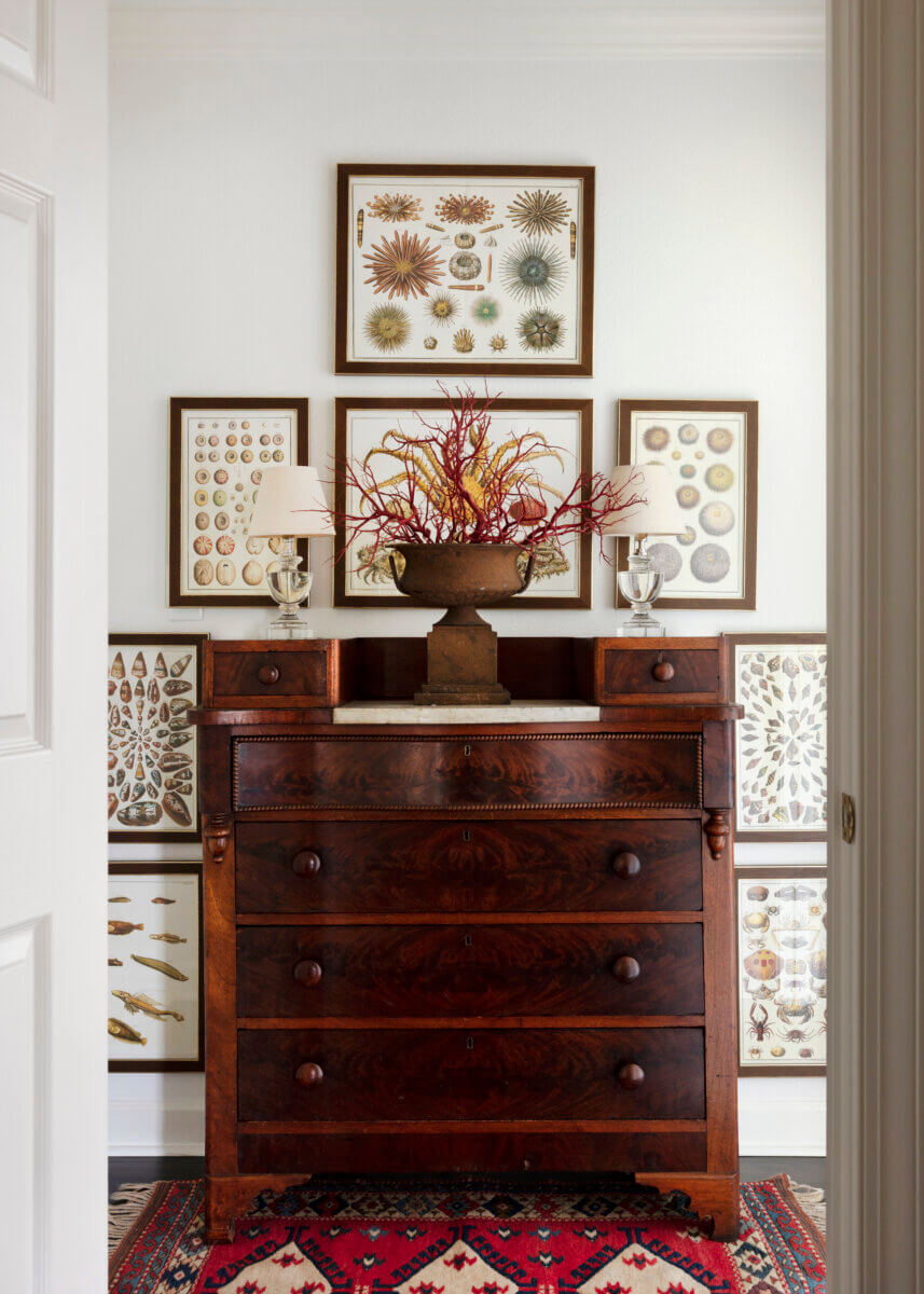 An interior design image of an armoire surrounded by framed pictures of shells.
