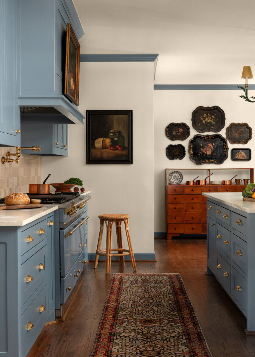 A kitchen features blue cabinetry and art.