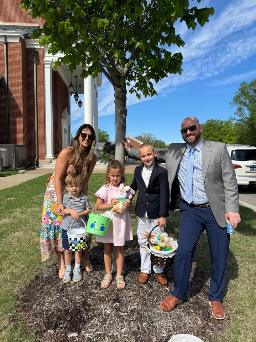 How Kelcie Nollner Built a Beloved Memphis Salad Destination - 4 A family of five, dressed in spring clothes, stands under a tree with Easter baskets on a sunny day outside a brick building.
