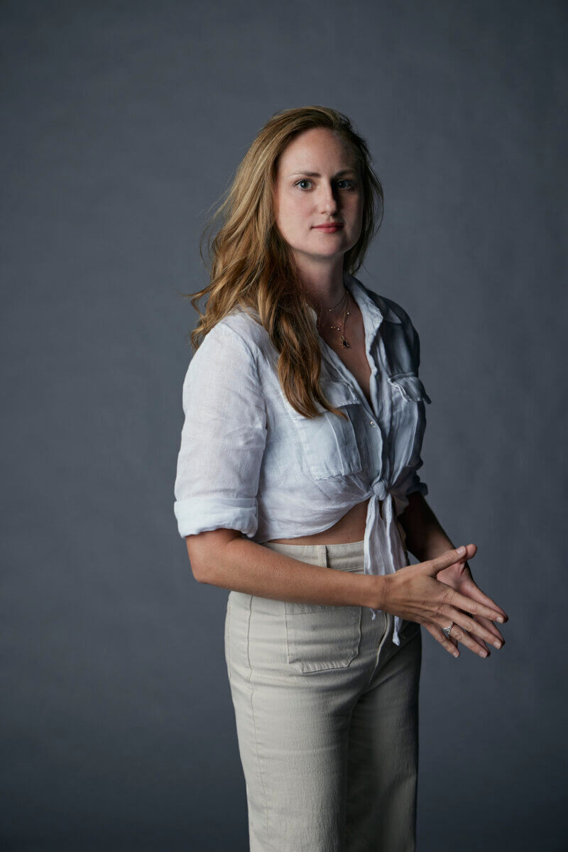 This Memphis Filmmaker is Reframing the Southern Story - 5 Suzannah Herbert stands against a plain gray background with long light brown hair, wearing a light-colored button-up shirt and beige pants.