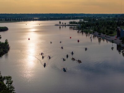 A group of kayakers paddles on a calm river at sunset, enjoying Memphis kayaking with reflections on the water and a tree-lined shoreline in the background.