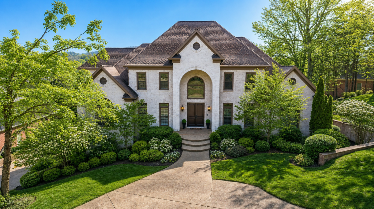 Just Listed! This Brentwood Estate Was Designed for Gathering, Entertaining & Everyday Living - 2 Two-story house at 513 Arden Wood Place with white brick exterior, brown roof, arched entryway, and landscaped front yard with shrubs and trees on a sunny day.