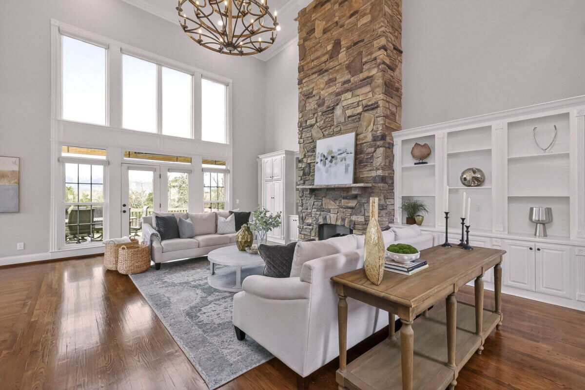 Just Listed! This Brentwood Estate Was Designed for Gathering, Entertaining & Everyday Living - 7 Spacious living room ideal for entertaining or everyday living, with large windows, a stone fireplace, light-colored sofas, a gray rug, and built-in shelves on a hardwood floor in this stunning Brentwood Estate.