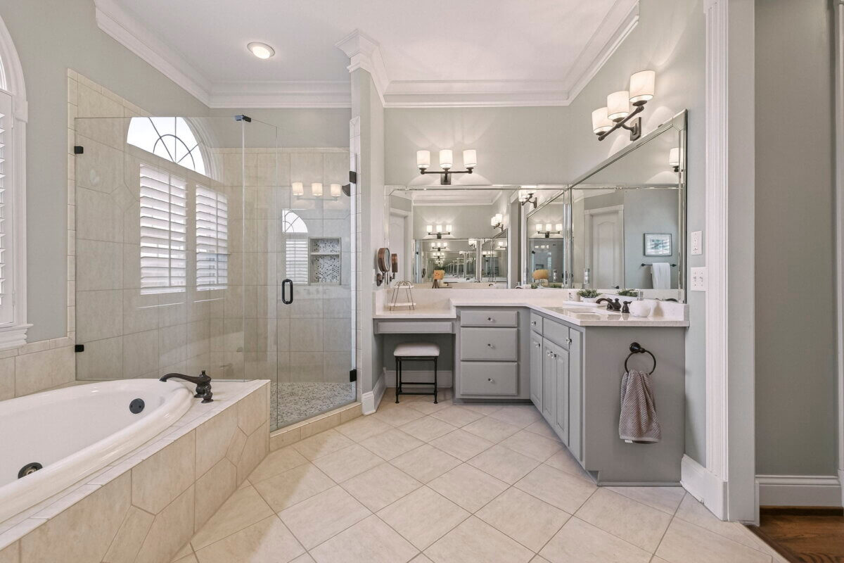 Just Listed! This Brentwood Estate Was Designed for Gathering, Entertaining & Everyday Living - 13 Modern bathroom in Brentwood Estate featuring a glass-enclosed shower, built-in bathtub, double vanity with mirrors, gray cabinets, and tiled floor—ideal for everyday living or entertaining guests.