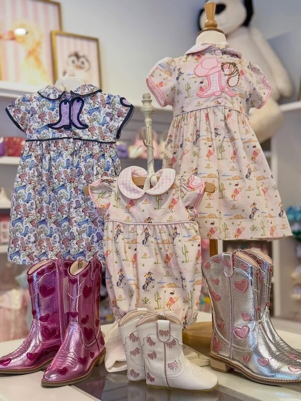 Your Guide to Nashville's Coolest Children's Stores - 5 Three children's dresses with pastel prints are displayed on mannequins, each paired with pink, white, or silver cowboy boots.