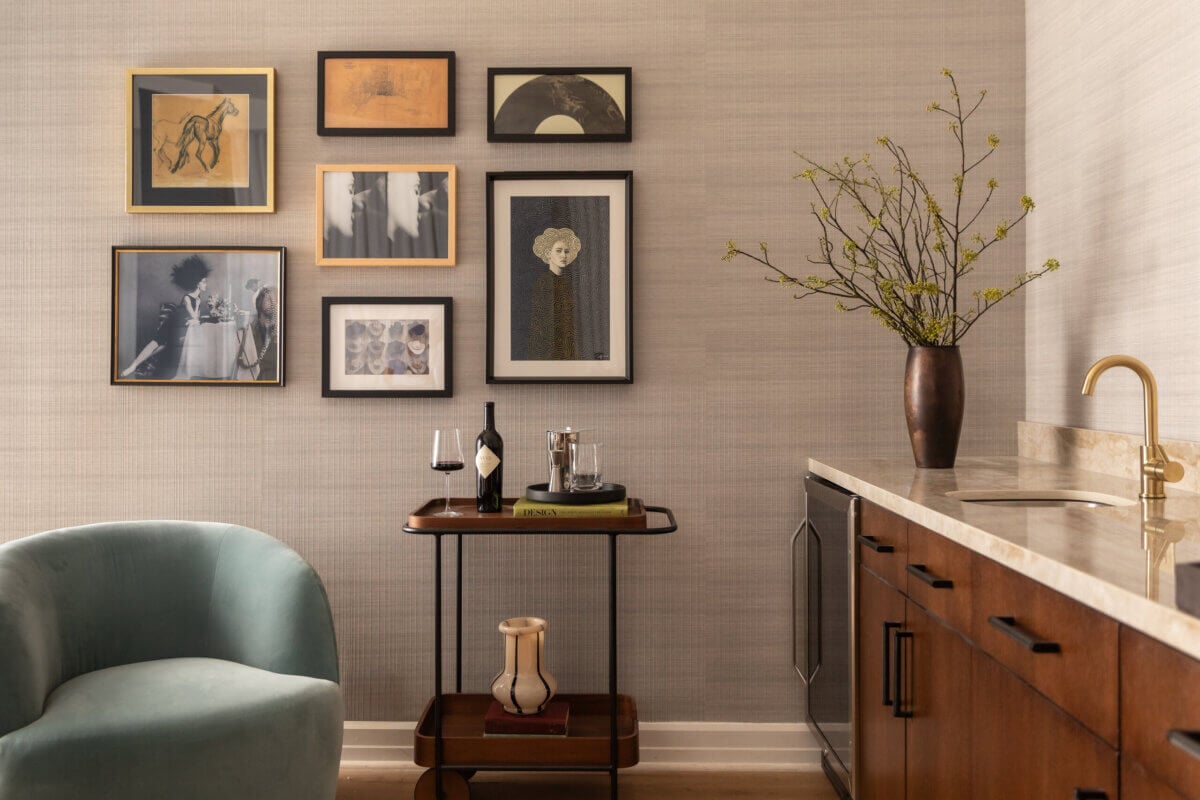 Nashville Steals, Deals & Announcements: June 2026 - 8 A modern living space with a green armchair, wall art, a bar cart with wine and glasses, and a counter with a vase of branches.