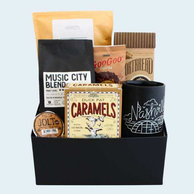 Nashville Steals, Deals & Announcements: June 2026 - 2 A black gift box features coffee, caramels, shortbread, a chocolate cluster, coffee pod, and a black mug with “Nashville” printed on it.