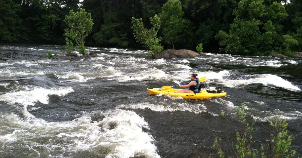 Epic Kayak Adventures in the South - 2 A person embarks on epic kayaking, paddling a yellow kayak through whitewater rapids in Wetumpka, Alabama.