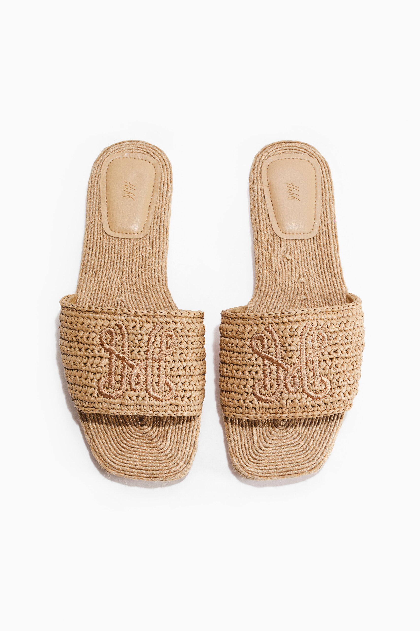 A pair of woven straw slide sandals with flat soles and wide straps, displayed together on a white background – perfect for embracing summer fashion trends.